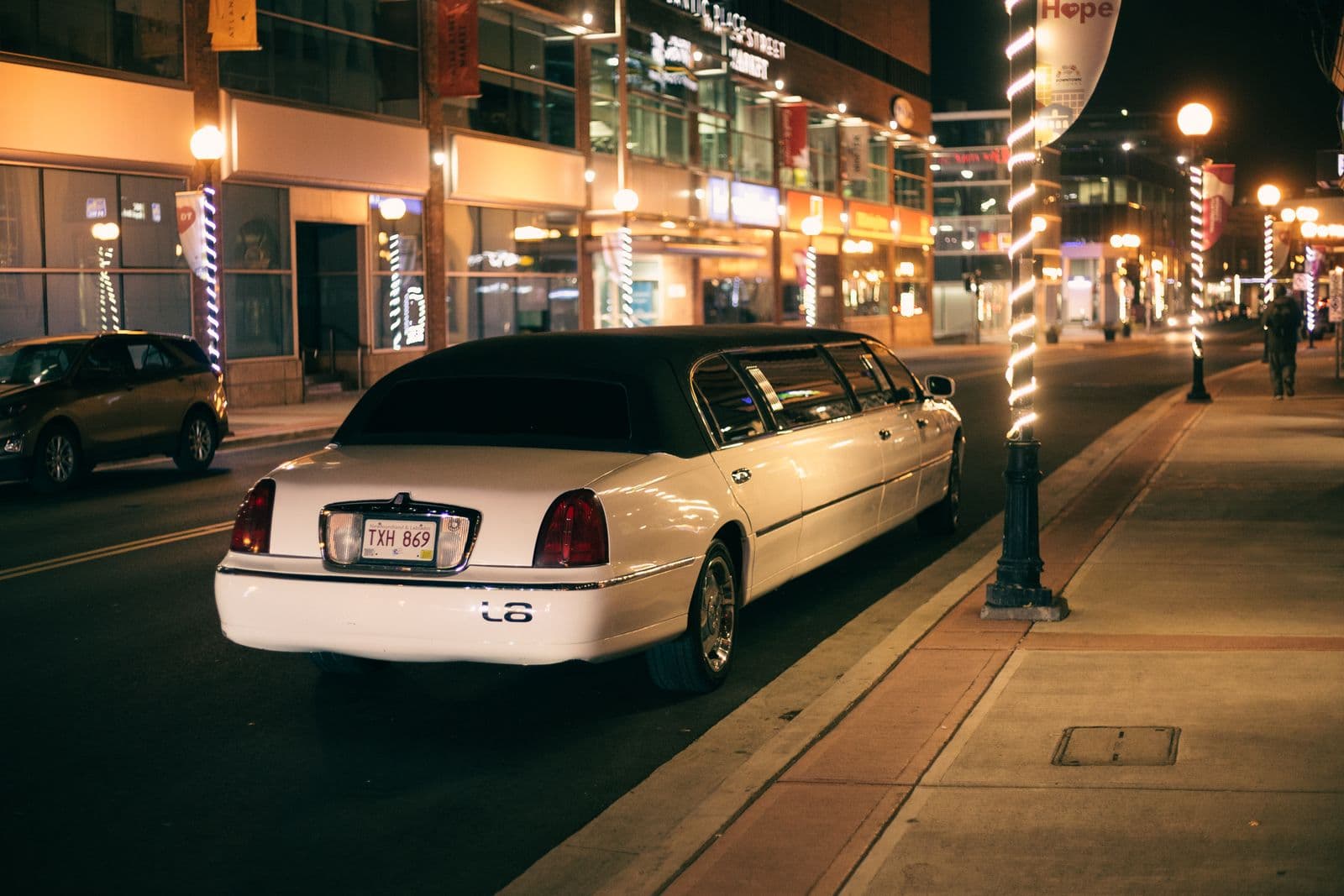 White stretch limousine waiting on a lit downtown street outside an evening venue