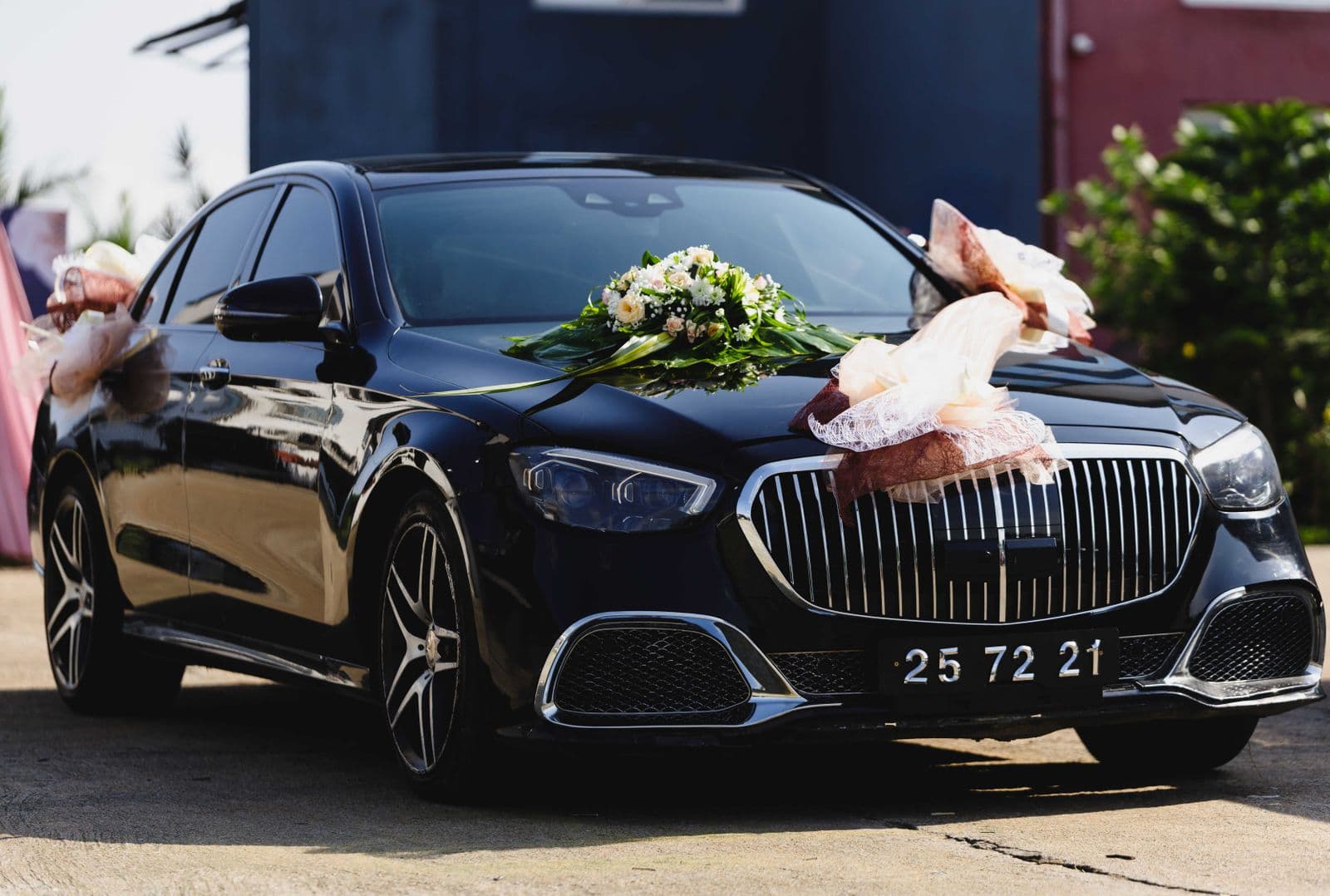 Black luxury sedan dressed with white wedding flowers outside the venue